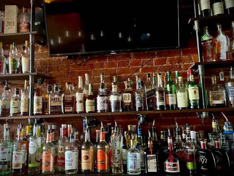 Backlit shelves of bourbon and whiskey behind the Old Town Smokehouse bar