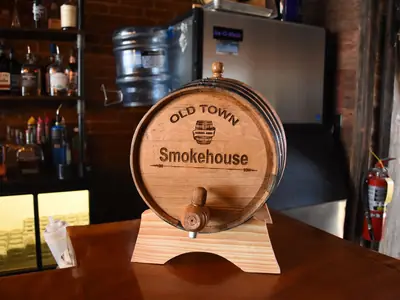 The engraved Old Town Smokehouse oak barrel used to age our Manhattans, on the bar