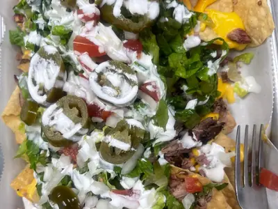 Smokehouse Nachos loaded with smoked brisket, cheese sauce, jalapeños, lettuce, tomato, onion and sour cream